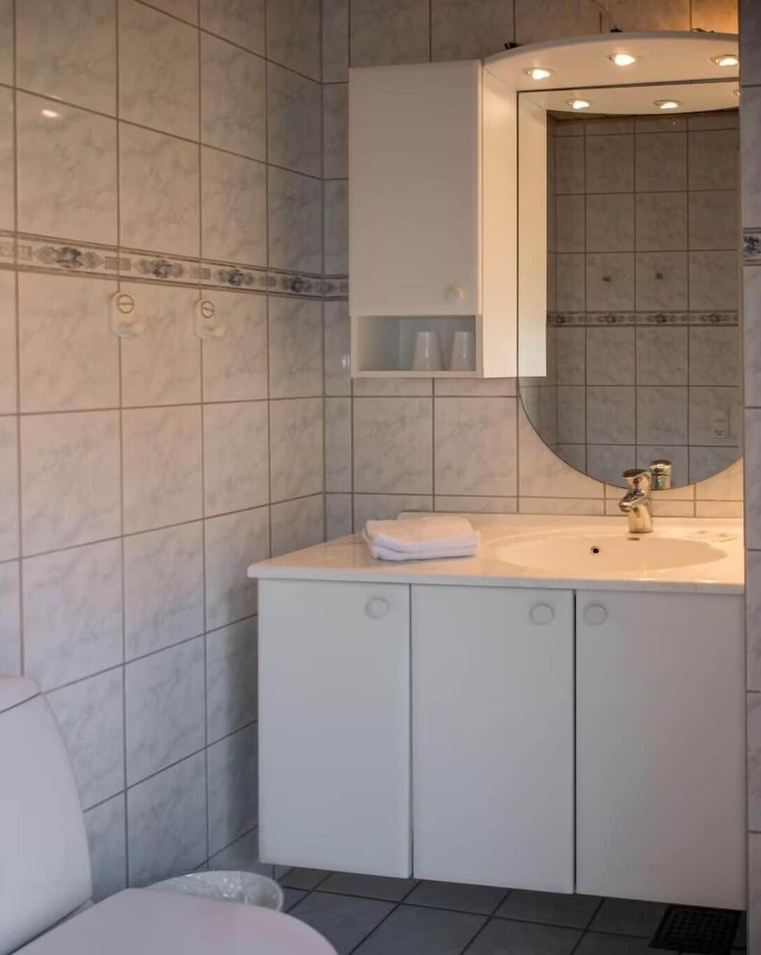 A bathroom with a white sink, a mirror, and a cabinet.