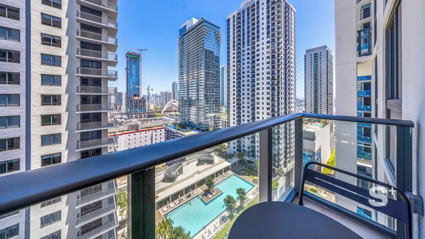 Un edificio alto con piscina en la azotea, varios balcones y una vista despejada del paisaje urbano.