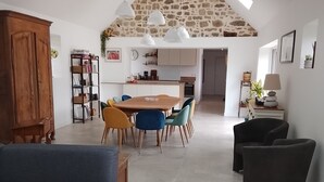 Een ruime woonkamer met een eettafel, een bank en een keuken op de achtergrond.