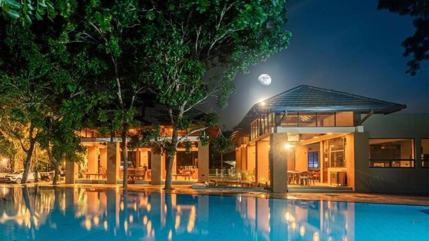A modern hotel with a swimming pool, large windows, and a moonlit night sky. - Paradise Bay Resort - Arugambay  (Arugambay)