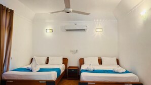 A hotel room with two wooden beds, a ceiling fan, an air conditioning unit, and a wall-mounted light fixture. - Paradise Bay Resort - Arugambay  (Arugambay)