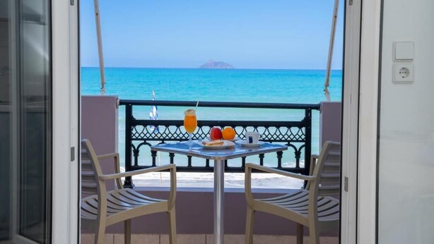 A balcony with a table and chairs, a drink, and a plate of fruit.