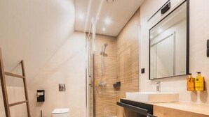 Een moderne badkamer met douche, toilet en wastafel.