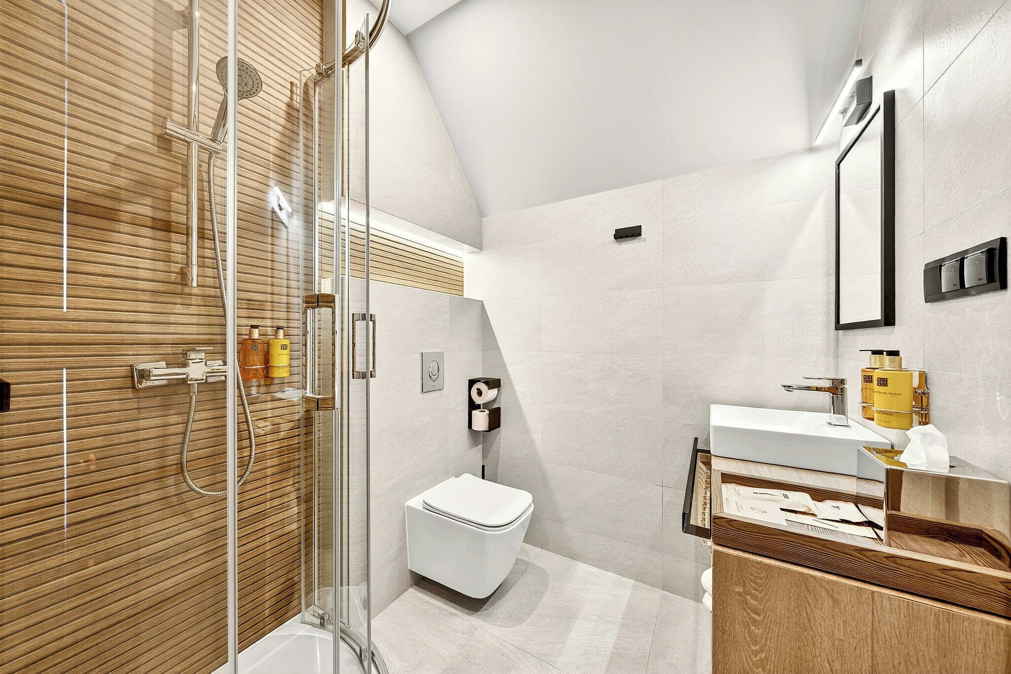 A modern bathroom with a glass-enclosed shower, a white toilet, and a wooden vanity with a mirror.