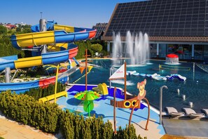A water park with slides, a pool, and a building with solar panels.