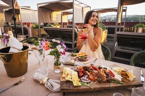 An outdoor dining area with a table set for a meal, including a variety of dishes and drinks.