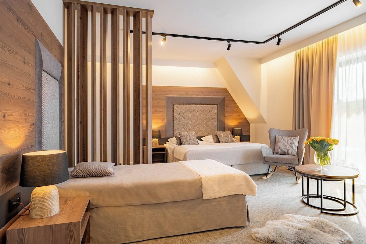 A modern hotel room with a large bed, a sofa, a desk, and a view of the city.