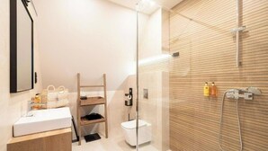 Een moderne badkamer met een houten wastafelmeubel, een glazen douchecabine en een toilet.