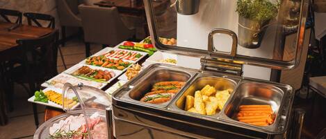 A buffet setup with various food items including sliced meats, vegetables, and prepared dishes.