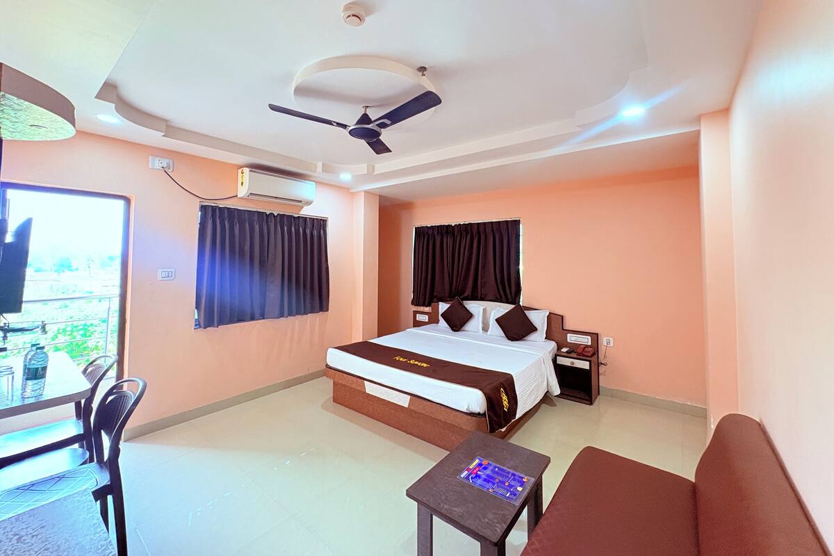 Una habitación de hotel con cama, escritorio, silla, ventilador de techo y aire acondicionado.