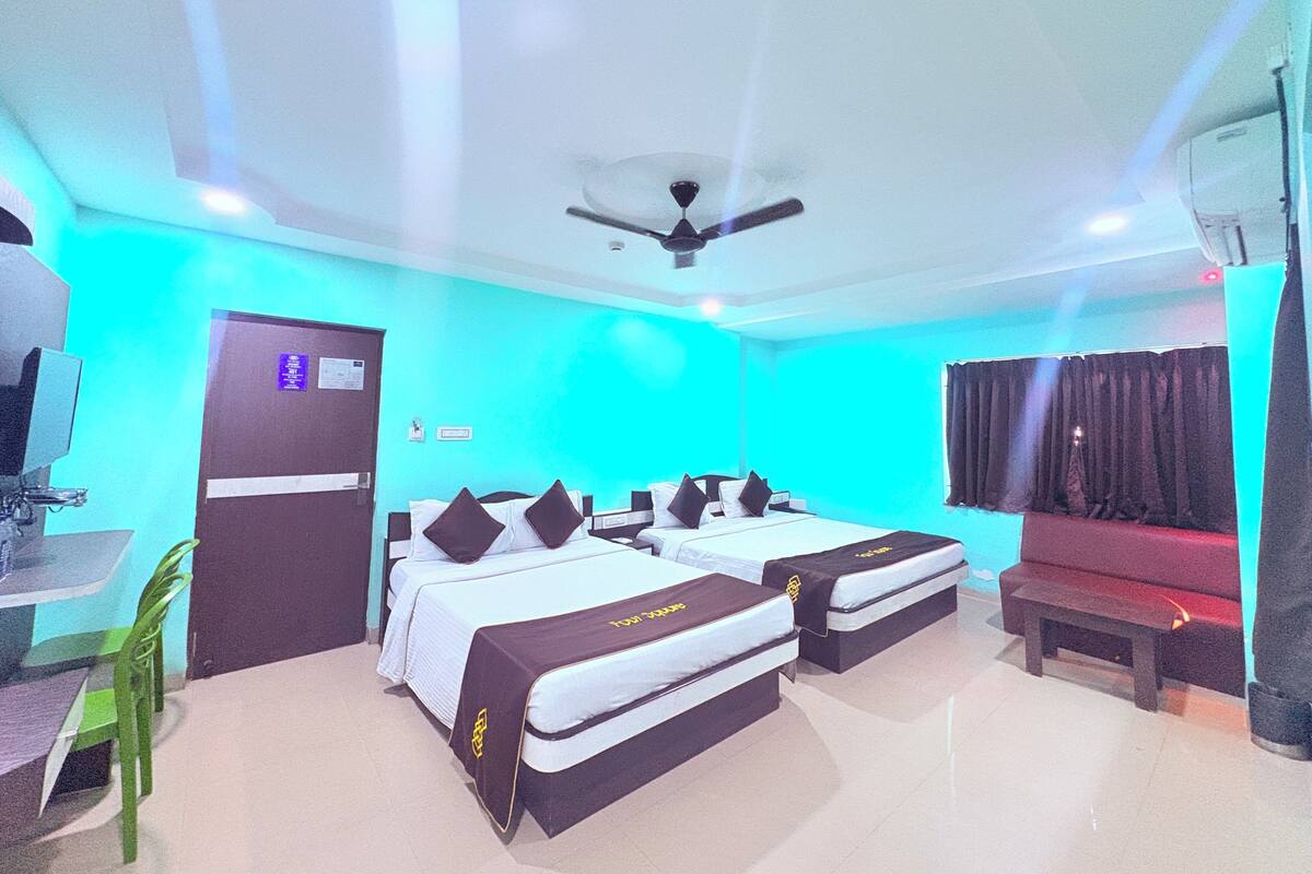 Una habitación de hotel con dos camas, un escritorio, una silla, un banco y un ventilador de techo.