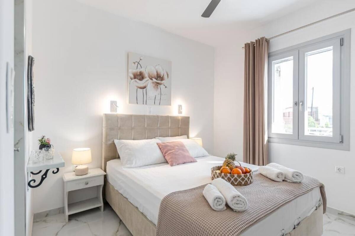A bedroom with a bed, nightstand, artwork, window, and towels.