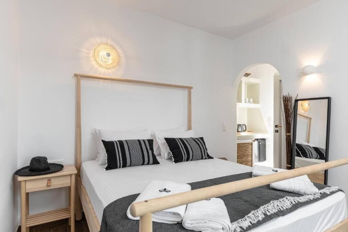 A bedroom with a bed, bedside tables, a mirror, and a wall-mounted light fixture.