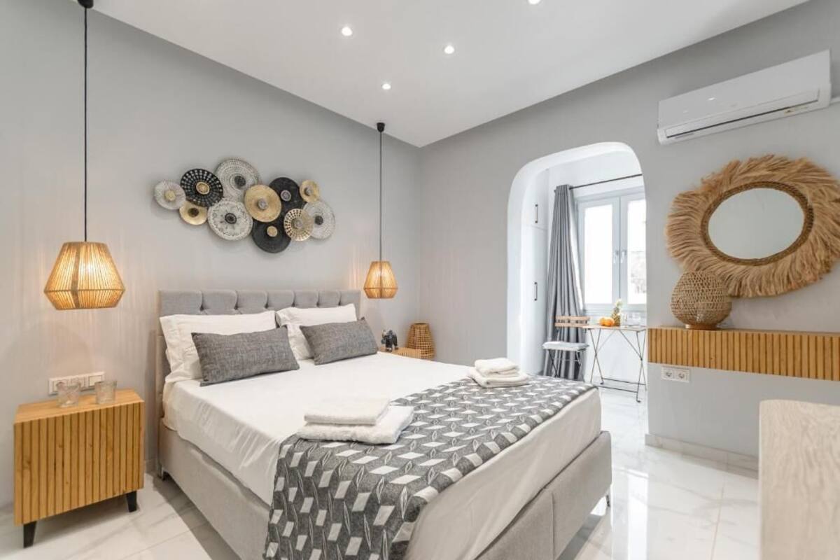 A modern bedroom with a large bed, bedside lamps, a wall art piece, and a mirror.
