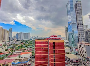 A cityscape with high-rise buildings, a prominent red building in the foreground, and a mix of commercial and residential structures. - TadaiManila Citadel Inn Makati (Makati City)