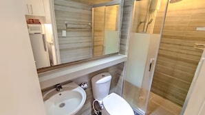 A bathroom with a sink, toilet, and shower. - TadaiManila Citadel Inn Makati (Makati City)