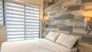 A bedroom with a bed, a bedside table, and a wall-mounted lamp. - TadaiManila Citadel Inn Makati (Makati City)