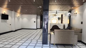 Un vestíbulo de hotel con suelo de baldosas, mostrador de recepción y zona de estar con sofás.