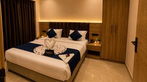 Una habitación de hotel con cama, mesita de noche, aire acondicionado de pared, ventilador de techo y armario de madera.