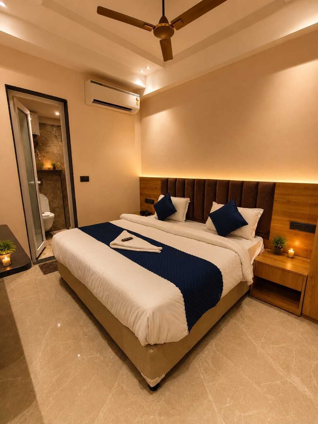 Una habitación de hotel moderna con una cama grande, un ventilador de techo, un equipo de aire acondicionado y una mesita de noche pequeña con una planta.