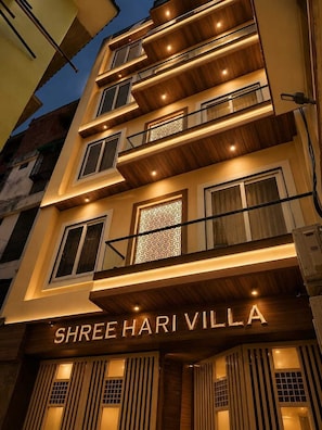 A multi-story building with balconies, a patterned facade, and the name 'SHREE HARI VILLA' displayed prominently.