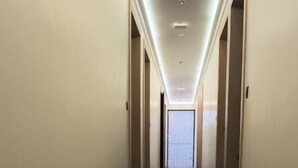 Un pasillo largo y estrecho con suelo reflectante, puertas a ambos lados e iluminación empotrada en el techo.