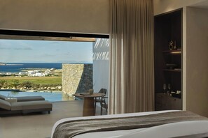 Ein modernes Hotelzimmer mit einem großen Bett, einem Balkon mit Meerblick und einem Essbereich mit Tisch und Stühlen.
