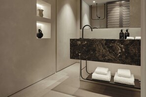 Ein modernes Badezimmer mit einem мраморный Waschtisch, einem Spiegel und zwei Handtüchern auf einem Regal.