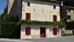 A building with a sign 'ASOLI' and red shutters, surrounded by greenery.