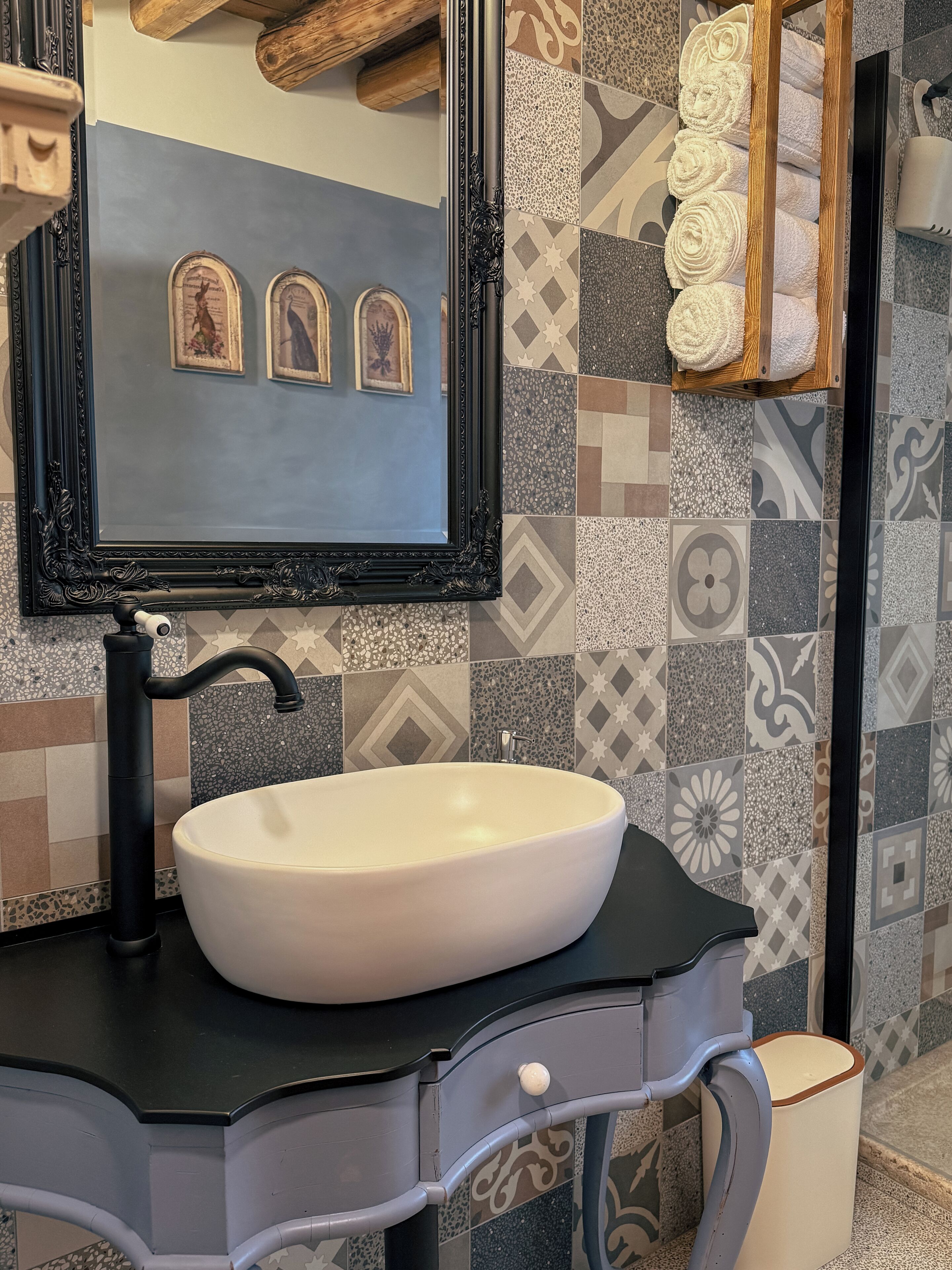 A bathroom with a large mirror, a white sink, and patterned tiles.