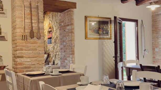 A dining area with a brick wall, wooden beams, and a table set for two.
