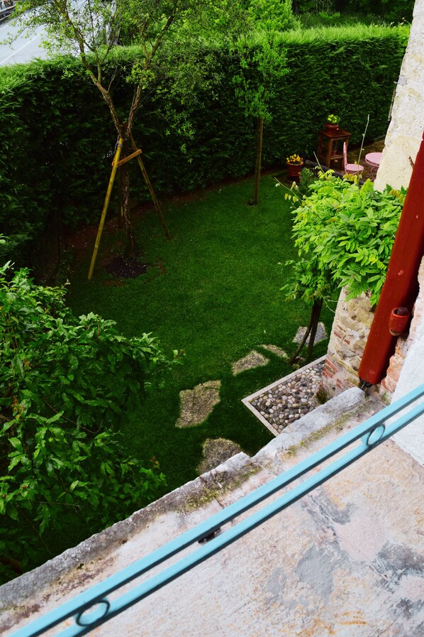 Un jardí amb gespa, una banca de fusta i una taula petita.