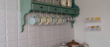 A kitchen with a green cabinet, white tiled backsplash, and a hanging pot rack.