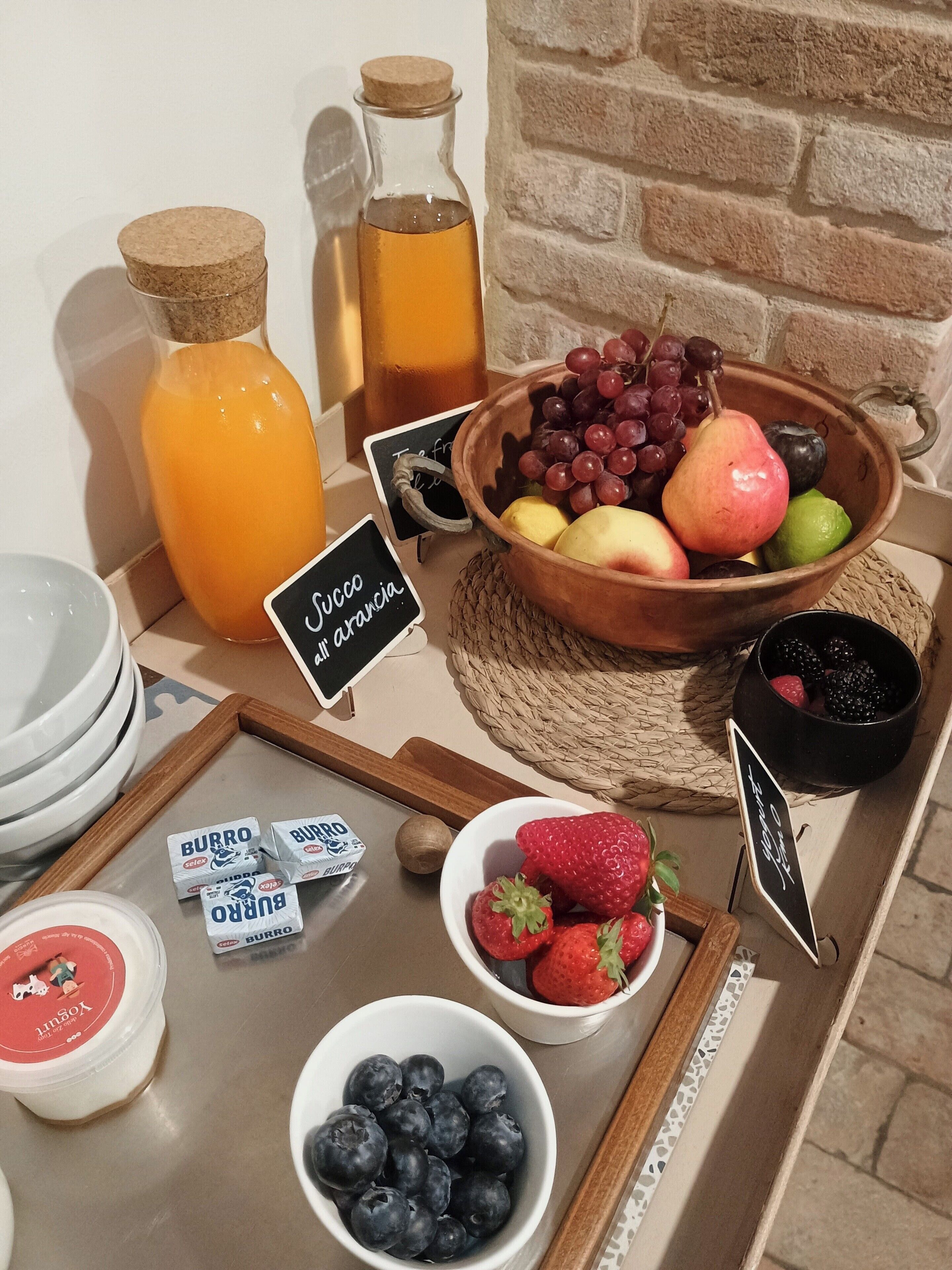 Een ontbijtbuffet met fruit, vruchtensappen en yoghurt parfait.