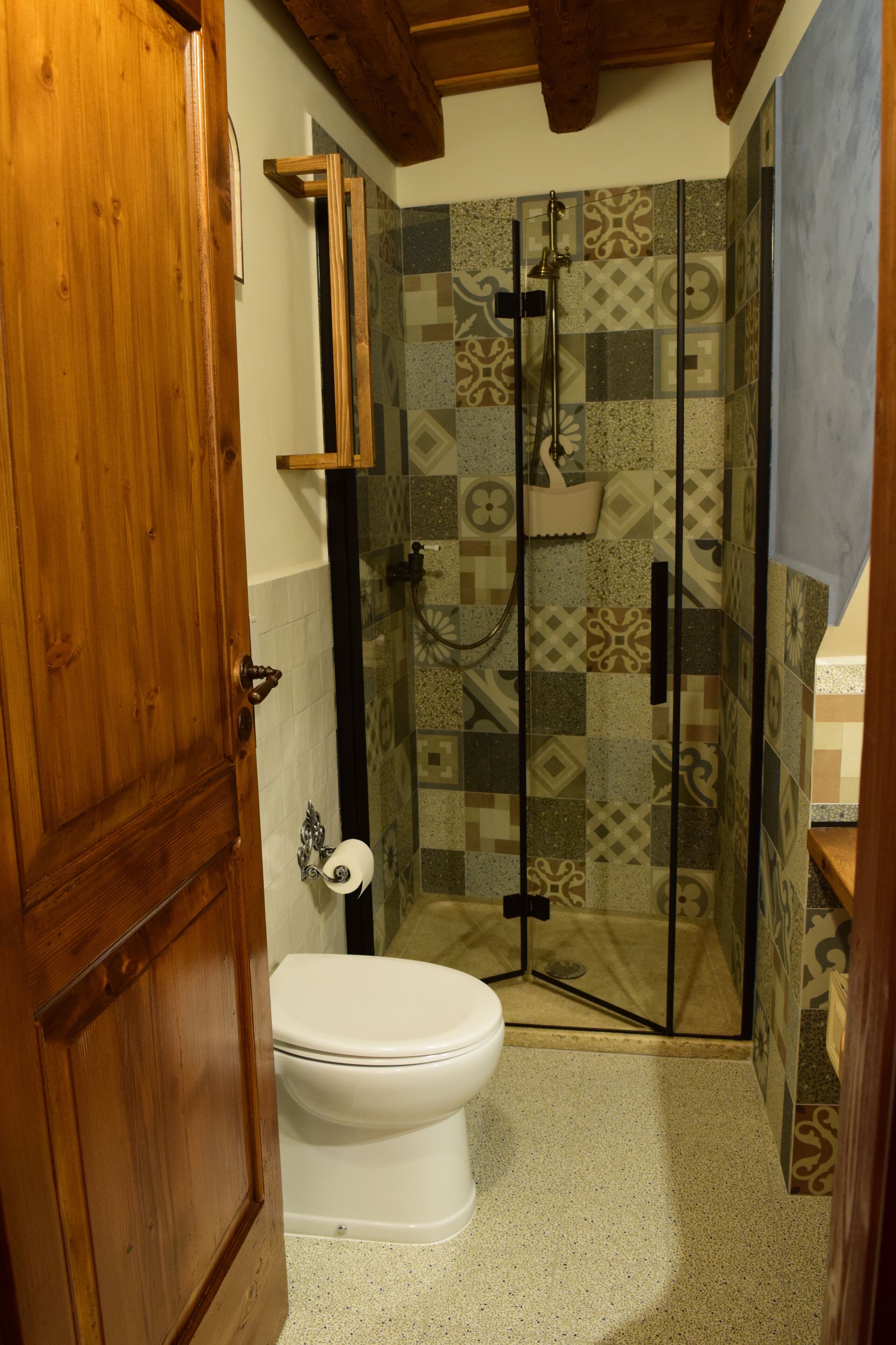 Un bagno con il water, una cabina doccia e una porta in legno.