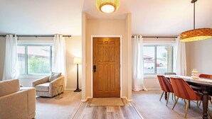 Un interno moderno con una porta in legno, un'area pranzo con sedie, un divano e una lampada.
