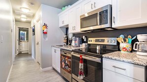 Una cocina moderna con armarios blancos, electrodomésticos de acero inoxidable y encimera de granito.