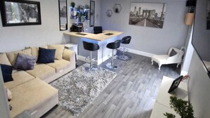 Ein modernes Wohnzimmer mit einer Couch, einer Essecke mit Bar und einer Treppe.