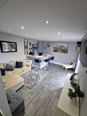 Ein modernes Wohnzimmer mit einer Couch, einer Essecke mit Bar und einer Treppe.