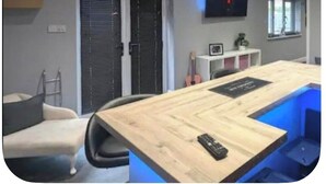 Ein modernes Zimmer mit Holztisch, Stühlen, einem Fernseher und einem Fenster.