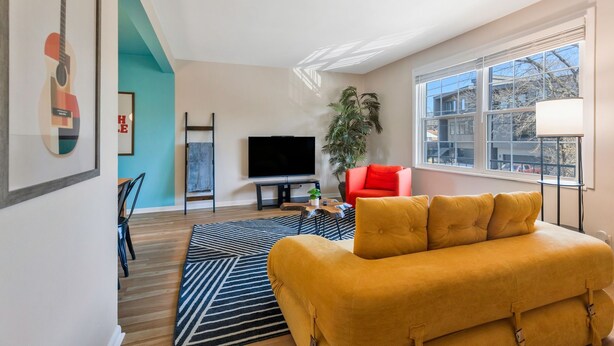 A modern living room with a sofa, television, and a large window. - Vinyl & Velvet w/ Parking near Vandy/DTWN (Nashville)