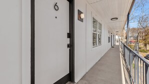 A corridor with a white door marked with the number 6, a black door frame, and a light fixture above the door. - Vinyl & Velvet w/ Parking near Vandy/DTWN (Nashville)