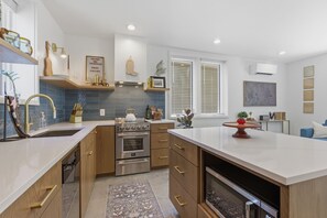 A modern kitchen with wooden cabinets, a central island, and a built-in oven. - Boots, Guitars & Bluebird Nights (Nashville)