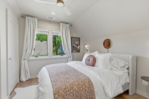 A bedroom with a bed, a window with curtains, a ceiling fan, a wall-mounted lamp, and a framed picture. - Boots, Guitars & Bluebird Nights (Nashville)