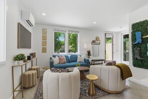 A modern living room with a blue sofa, white armchairs, a coffee table, and a green wall decoration. - Boots, Guitars & Bluebird Nights (Nashville)