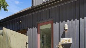 Un edificio con fachada gris, una puerta roja y un buzón con el número 409.