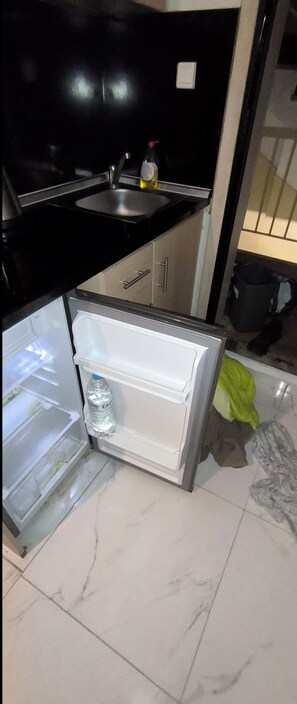 Eine Küche mit Kühlschrank, Spüle und einer Tasche auf dem Boden.