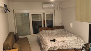 A bedroom with a bed, a desk, a chair, a wardrobe, and a window with blinds. - Thessalonik Apartment-heart of City (Thessaloniki)