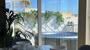 Une table à manger avec de beaux verres transparents, une nappe blanche et une vue sur une clôture blanche à treillis et sur la verdure environnante.