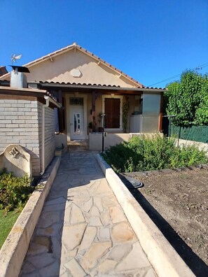 A house with a stone pathway leading to the entrance, a brick wall, and a garden area. - Nice little house for visiting the little province and the Camargue. (Arles)